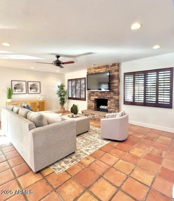 tiled living room featuring a stone fireplace and ceiling fan