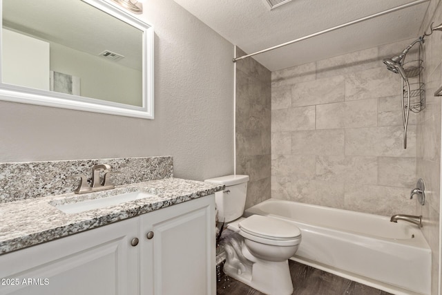 full bathroom featuring wood-type flooring, tiled shower / bath, toilet, a textured ceiling, and vanity