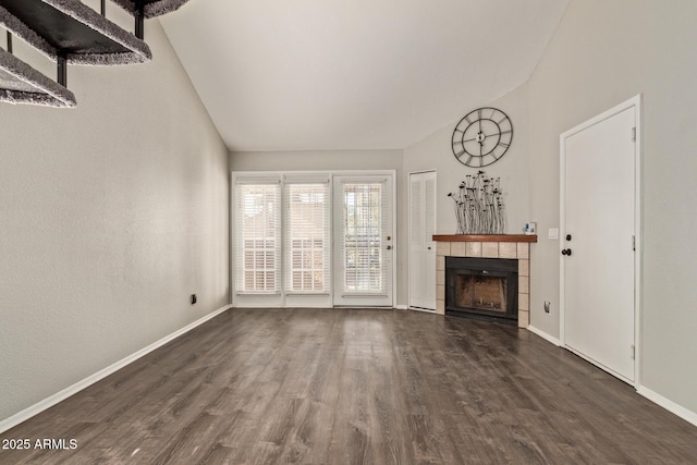 unfurnished living room with a tiled fireplace, lofted ceiling, and dark hardwood / wood-style flooring