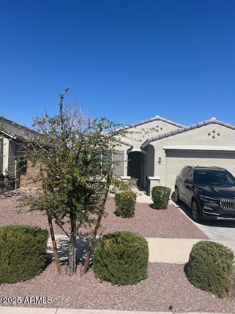 view of home's exterior with a garage, concrete driveway, a tile roof, and stucco siding