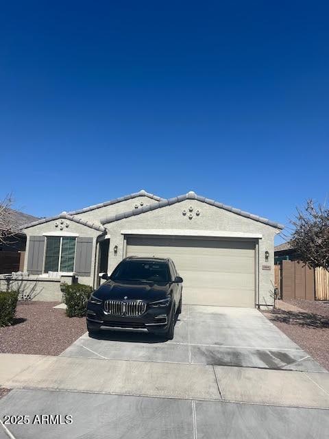 ranch-style house with a garage, concrete driveway, fence, and a tiled roof