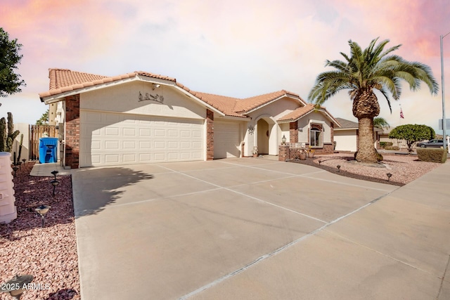 mediterranean / spanish-style home featuring an attached garage, driveway, a tile roof, and stucco siding