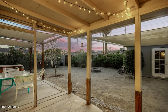 patio terrace at dusk with an outdoor fire pit and a hot tub