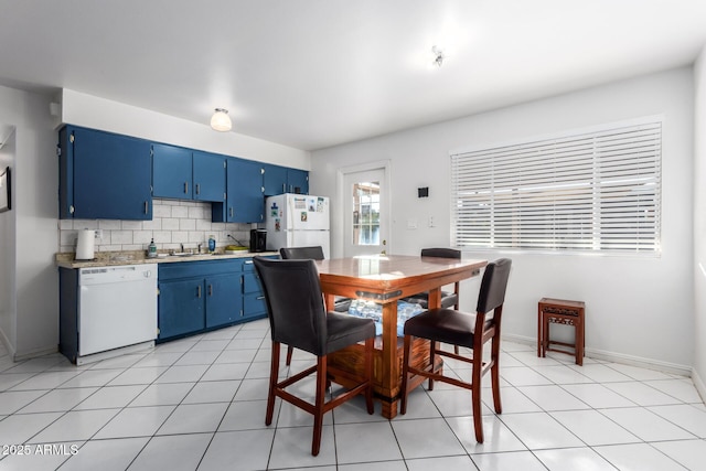 kitchen featuring sink, backsplash, blue cabinetry, light tile patterned floors, and white appliances