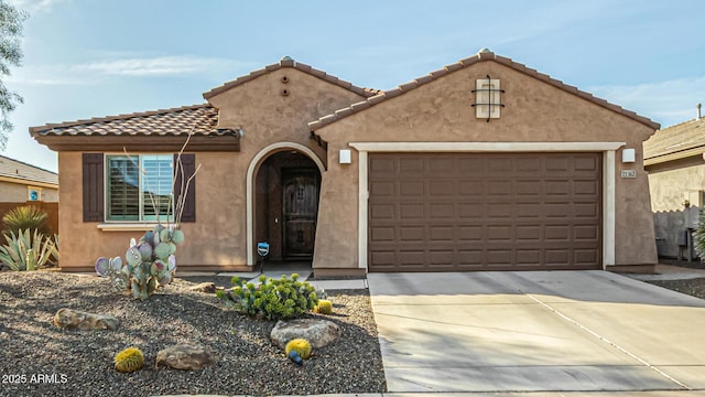 mediterranean / spanish house with a garage, driveway, a tiled roof, and stucco siding