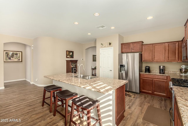 kitchen with arched walkways, a breakfast bar area, visible vents, appliances with stainless steel finishes, and a sink