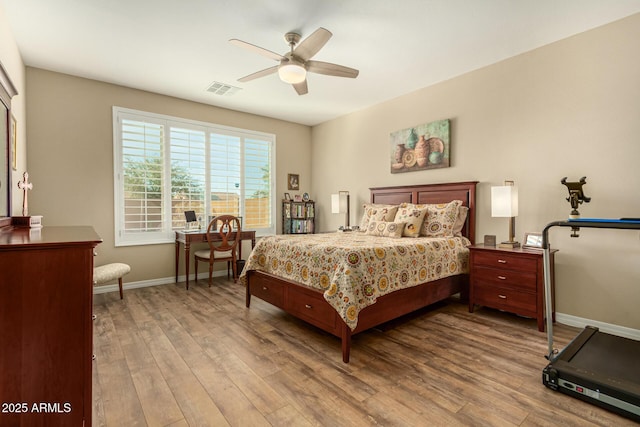 bedroom featuring a ceiling fan, baseboards, visible vents, and wood finished floors