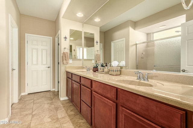 full bath featuring double vanity, a stall shower, baseboards, and a sink