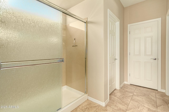 full bath with a shower stall and baseboards