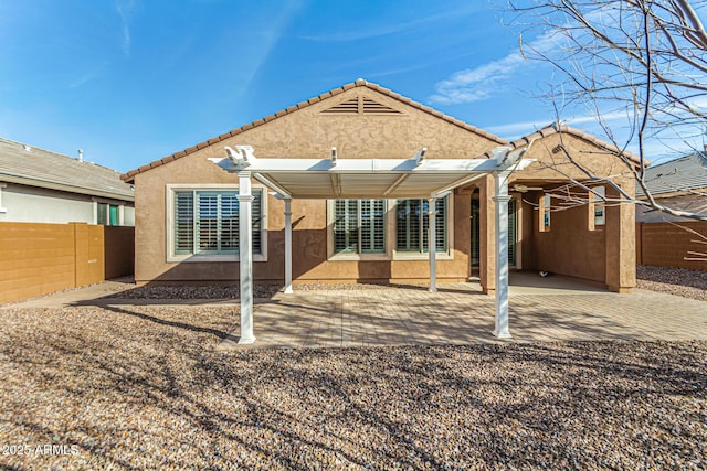 rear view of house with a patio, a tile roof, fence, and stucco siding