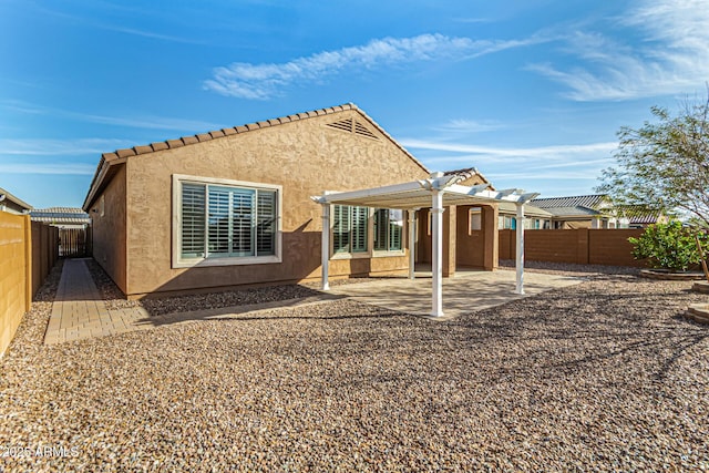 rear view of house featuring stucco siding, a patio, a fenced backyard, and a pergola