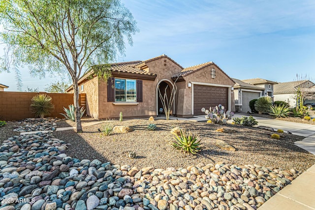 mediterranean / spanish-style house with a garage, concrete driveway, a tile roof, fence, and stucco siding