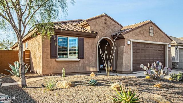 view of front of home featuring a garage, a tiled roof, fence, and stucco siding