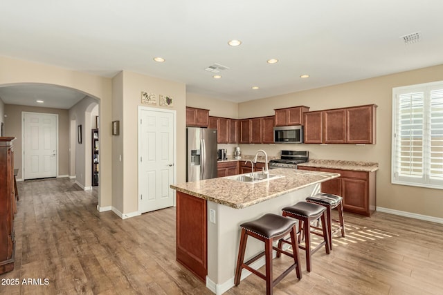 kitchen with appliances with stainless steel finishes, light wood-type flooring, a sink, and visible vents