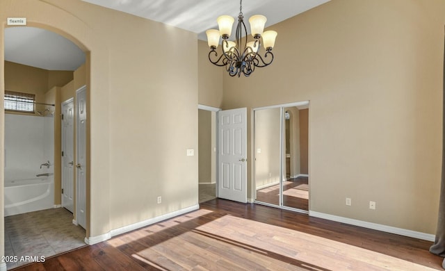 unfurnished bedroom featuring hardwood / wood-style flooring and an inviting chandelier