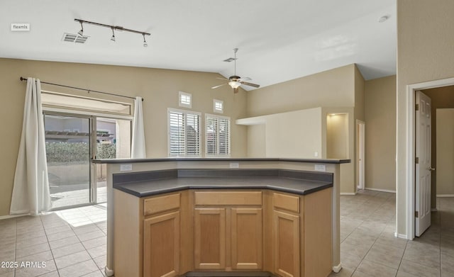 kitchen featuring an island with sink, vaulted ceiling, light tile patterned flooring, and ceiling fan