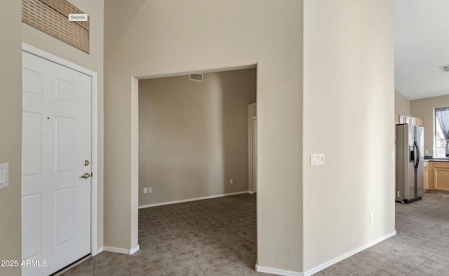 hallway with lofted ceiling and light tile patterned floors