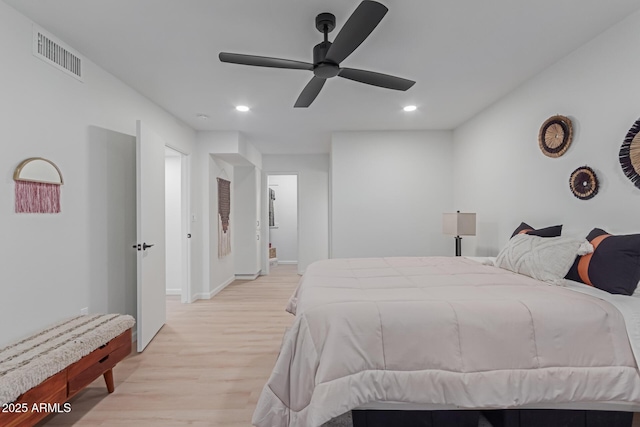 bedroom with light wood-type flooring, ceiling fan, and ensuite bath