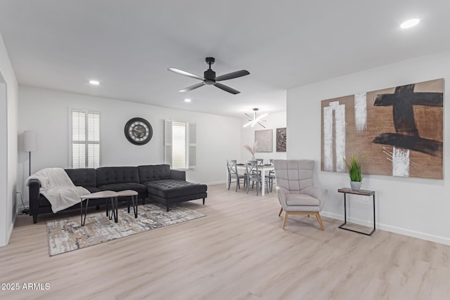 living room with ceiling fan with notable chandelier and light hardwood / wood-style flooring