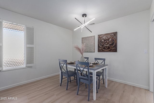 dining area with light hardwood / wood-style flooring and a chandelier