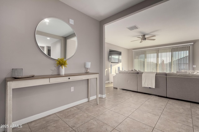 unfurnished living room with ceiling fan, light tile patterned floors, and baseboards