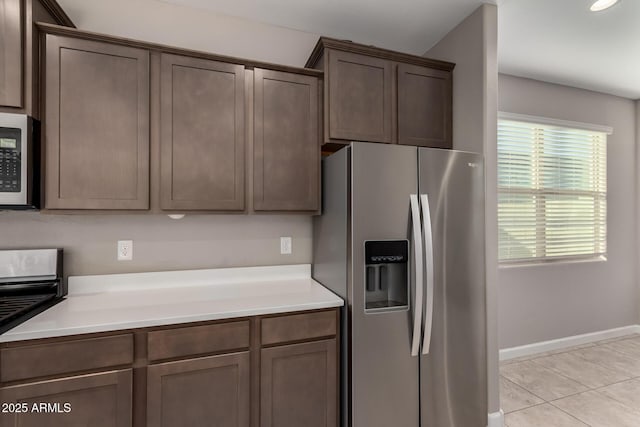 kitchen featuring dark brown cabinetry, light tile patterned floors, light countertops, and stainless steel fridge with ice dispenser