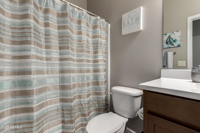 bathroom with a textured wall, vanity, and toilet