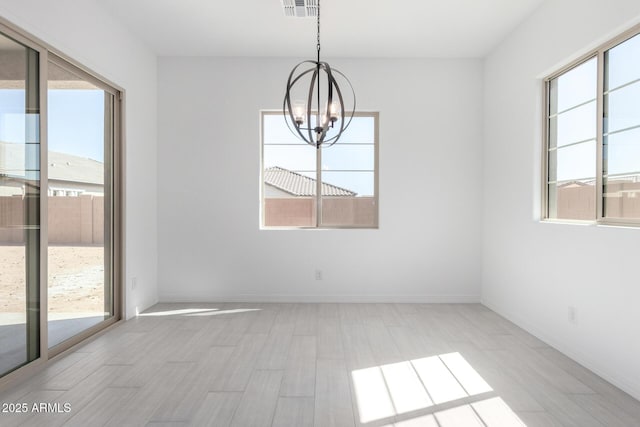 unfurnished dining area with visible vents, a healthy amount of sunlight, a chandelier, and baseboards