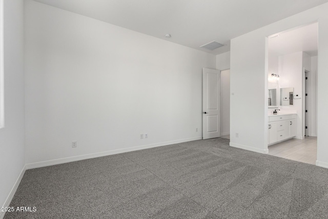 unfurnished bedroom with baseboards, visible vents, light carpet, and a sink