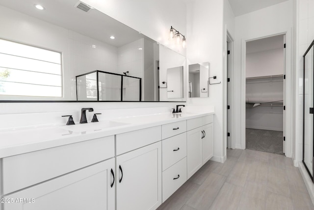 full bath with visible vents, a spacious closet, a stall shower, and a sink