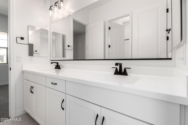 bathroom featuring double vanity, a sink, and baseboards