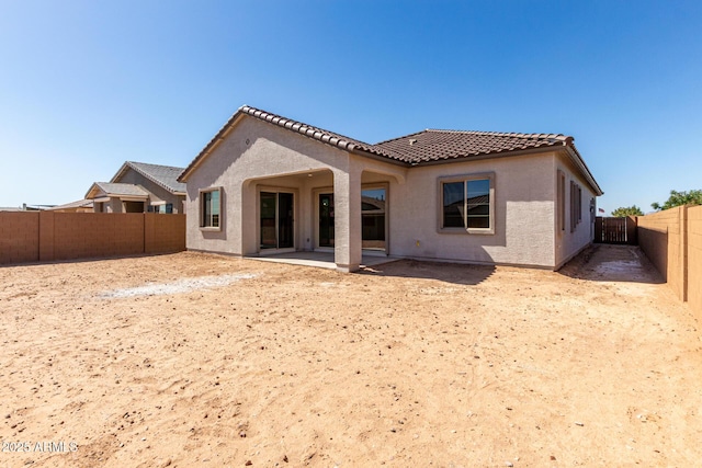 rear view of property featuring stucco siding, a fenced backyard, a patio, and a tile roof