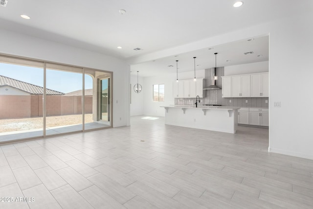 unfurnished living room with visible vents, recessed lighting, and a sink