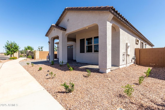 view of front of house with a gate, fence, stucco siding, and a tiled roof