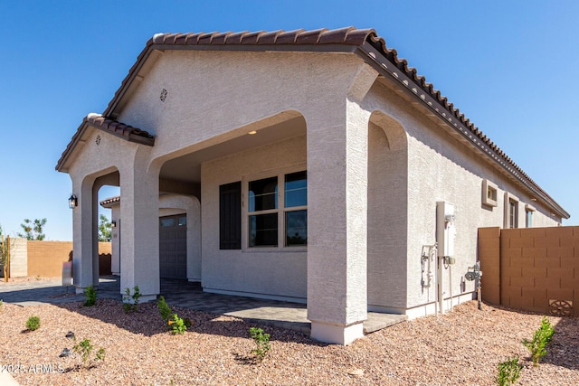 view of front facade with a tile roof, stucco siding, and fence