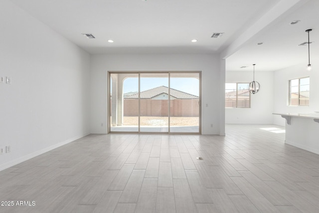 empty room with light wood-type flooring, visible vents, and a notable chandelier