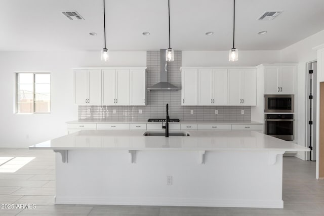kitchen with visible vents, stainless steel appliances, backsplash, and wall chimney exhaust hood
