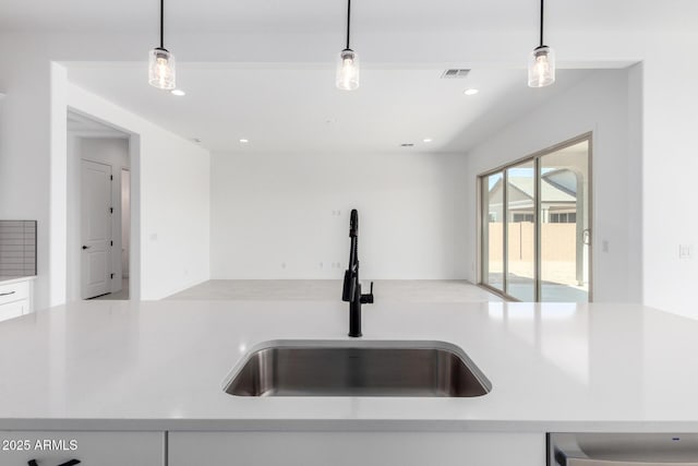 kitchen featuring hanging light fixtures, open floor plan, light countertops, and a sink
