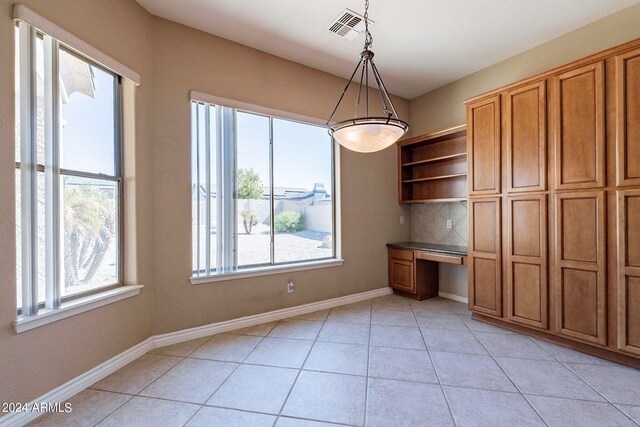 unfurnished dining area featuring built in desk and light tile patterned flooring