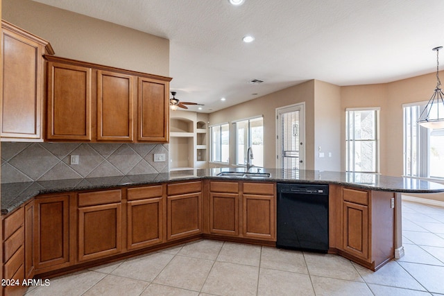 kitchen featuring dark stone counters, dishwasher, sink, ceiling fan, and hanging light fixtures