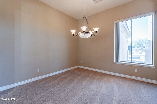 carpeted spare room featuring a chandelier, visible vents, baseboards, and lofted ceiling