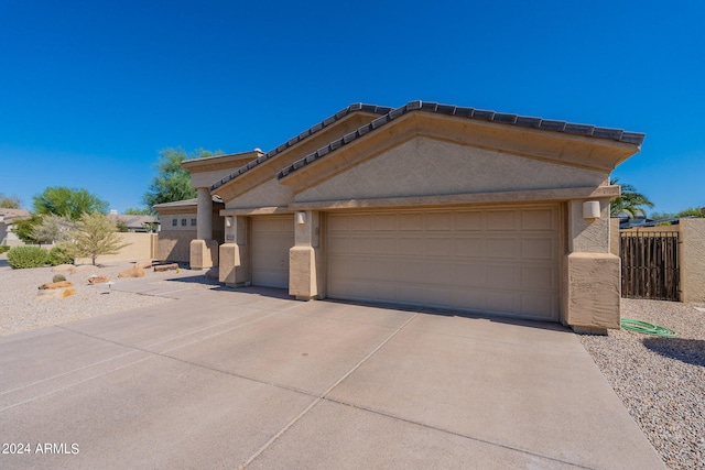 view of front of property featuring stucco siding, concrete driveway, a garage, and fence