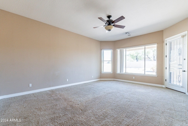 carpeted spare room featuring visible vents, baseboards, and ceiling fan