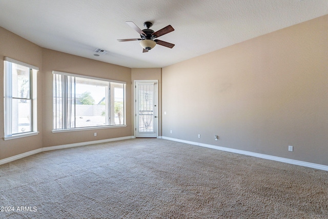 empty room with baseboards, visible vents, carpet floors, ceiling fan, and a textured ceiling