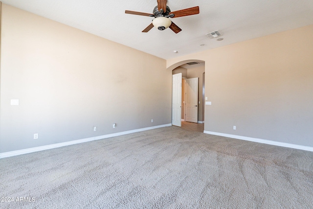 spare room with visible vents, light carpet, a ceiling fan, arched walkways, and baseboards