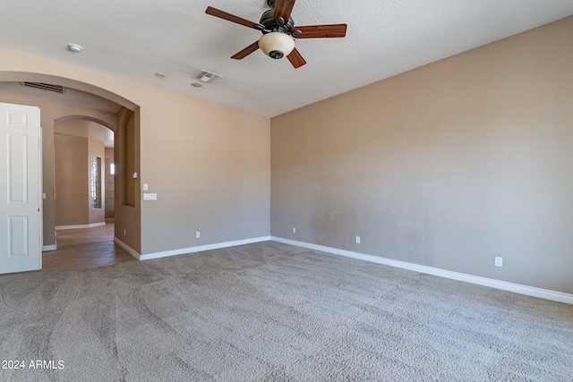 spare room featuring carpet, visible vents, arched walkways, and baseboards