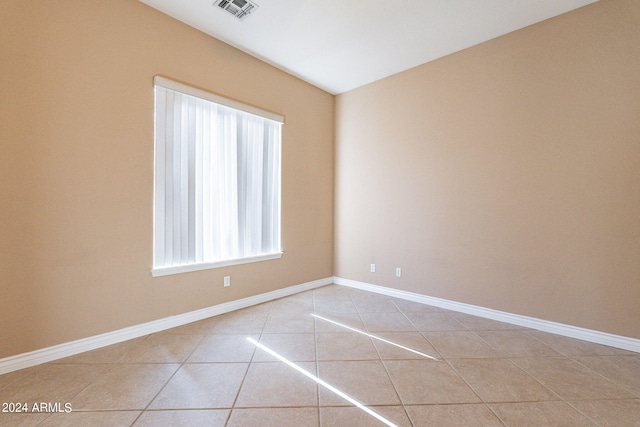 empty room featuring light tile patterned floors, visible vents, and baseboards