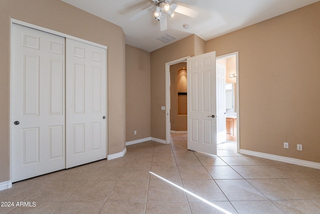 unfurnished bedroom with baseboards, visible vents, light tile patterned flooring, ceiling fan, and a closet