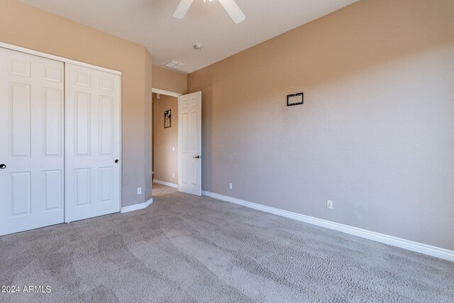 unfurnished bedroom with light colored carpet, ceiling fan, and a closet