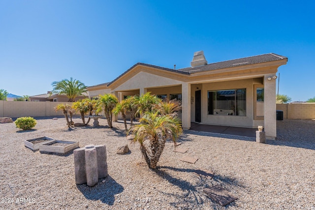 back of property featuring fence, a chimney, and stucco siding